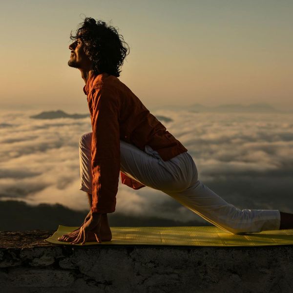 Silhouette of a man stretching against a sunrise, feeling energized.
